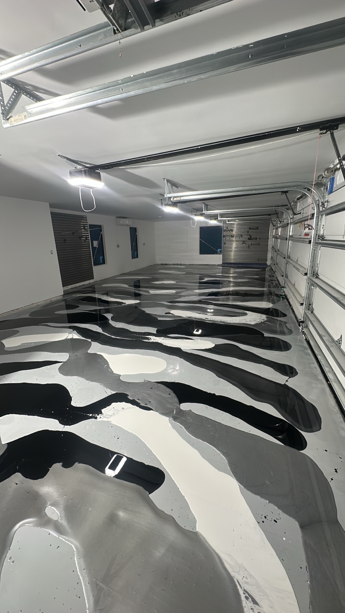 Black, white, and silver metallic epoxy being poured across a four-car garage