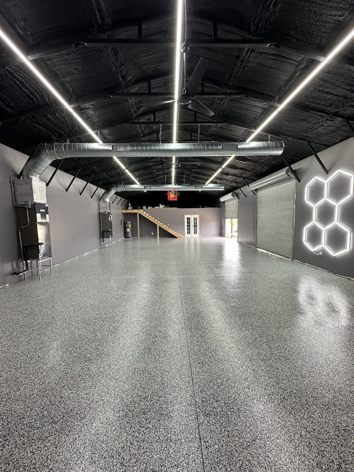 Wide view of completed gray flake floor in an industrial warehouse-style garage